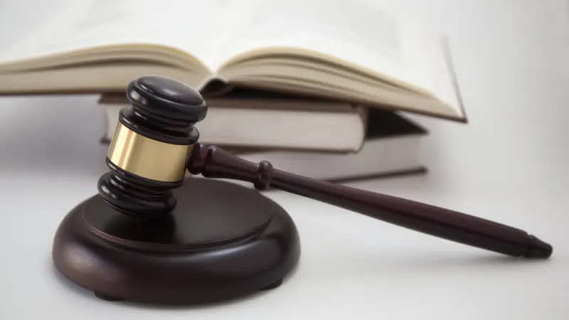 A wooden gavel resting in front of a stack of open law books.